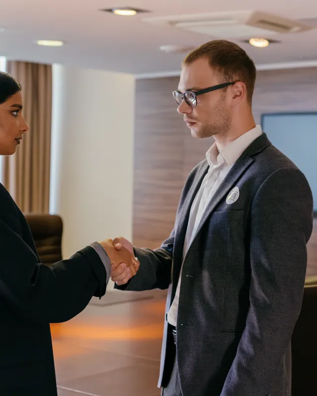 Two professionals shaking hands in a bright meeting room